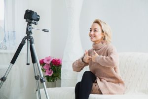 Young female vlogger next to camera at home. recording video for blog