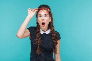 Surprised woman in red glasses amazement looking at camera