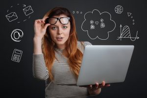 Smart confident person holding the glasses while standing with a laptop