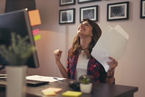 Woman holding documents joyful after a business success