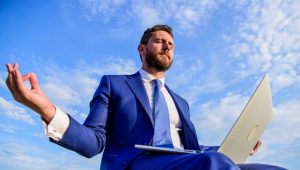 Man try keep his mind clear. Entrepreneur find minute relax and meditate. Work online can be annoying. Communication online full of bullying. Businessman formal suit with laptop meditating outdoors