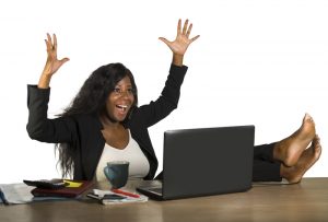 happy and attractive black afro American businesswoman working excited with feet on computer desk smiling relaxed celebrating business financial success