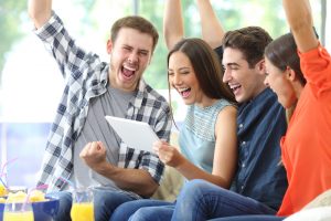 Excited group of friends watching media on tablet at home