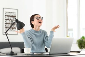 Happy female freelancer working with laptop in office