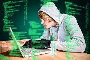 Focused man with hoodie typing on laptop against green background with vignette