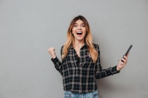 Happy excited girl holding mobile phone and celebrating win